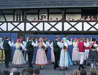 A folklore dance group dances in front of the byre